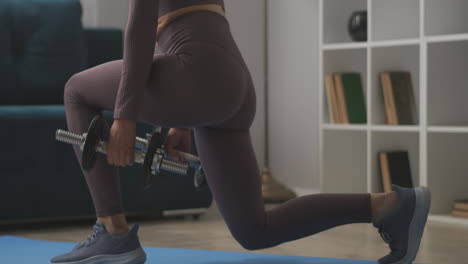 woman-is-doing-squats-with-dumbbells-training-at-home-closeup-view-of-body-slender-legs-buttocks-and-back-fitness-in-living-room